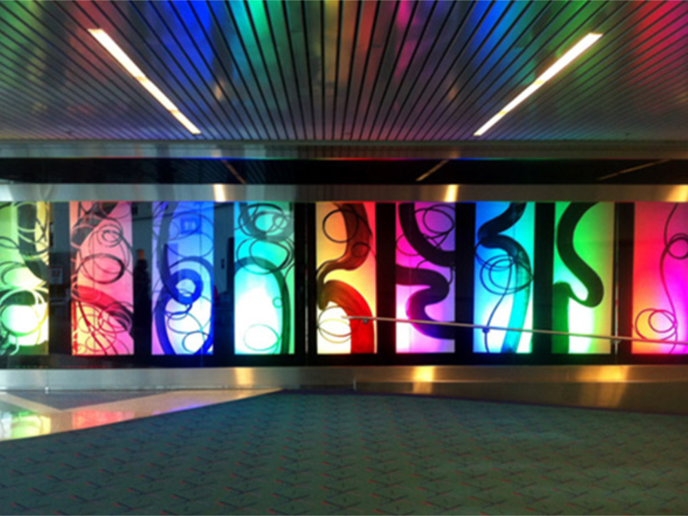Untangled installation at Portland International Airport, panels lit in shifting rainbow LED color