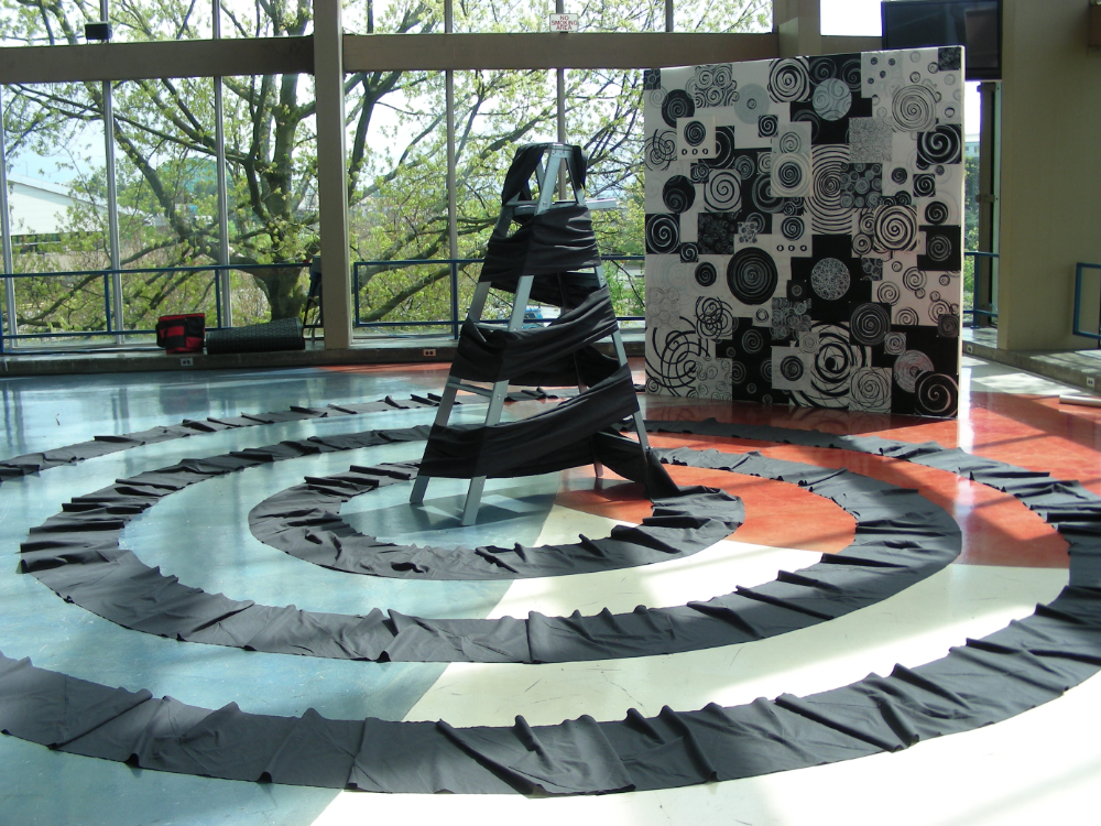Spiral installation of pleated black fabric with a fabric-wrapped ladder at center, Cascade AIDS Project