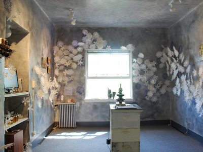 Full view of the See installation room with beehive box, wax flowers, and window