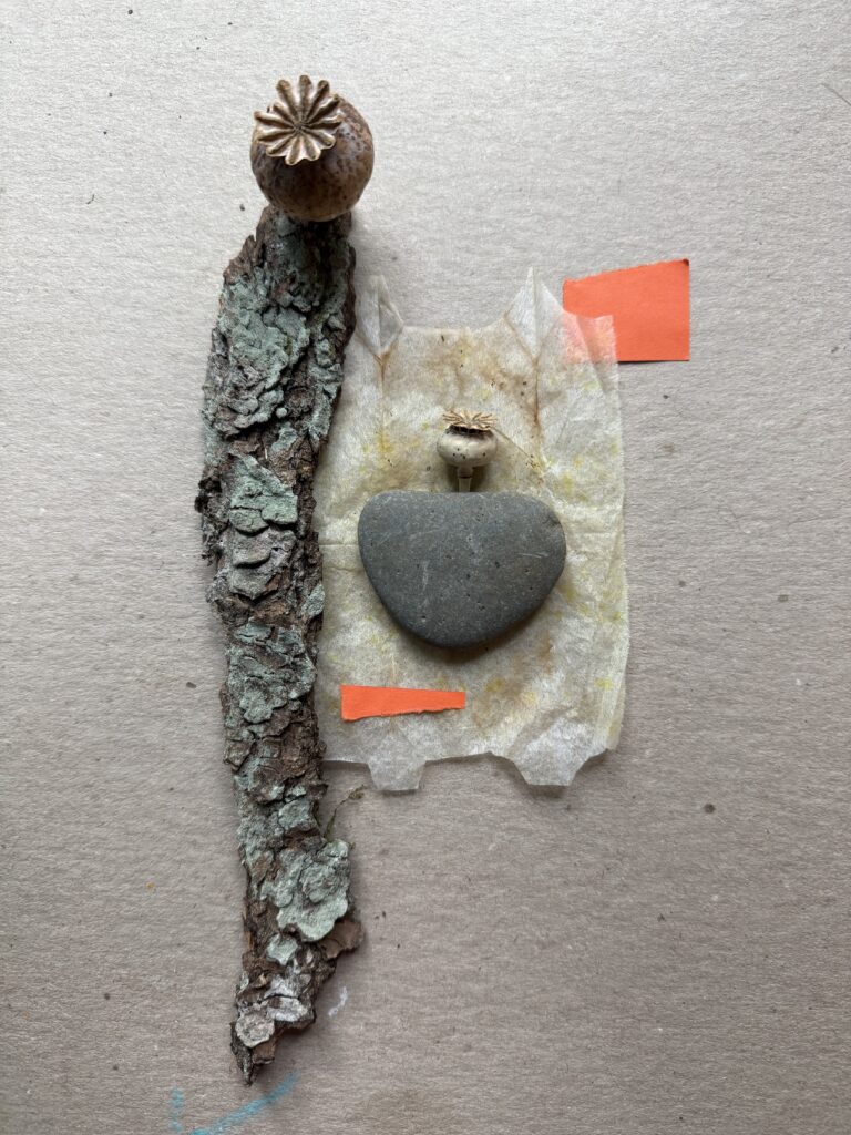 Temporary collage arrangement of a lichen-covered bark topped with a dried poppy seed pod, a smooth, flat grey stone, a second small poppy pod, torn and stained tea bag paper, and strips of orange paper, on cardboard.
